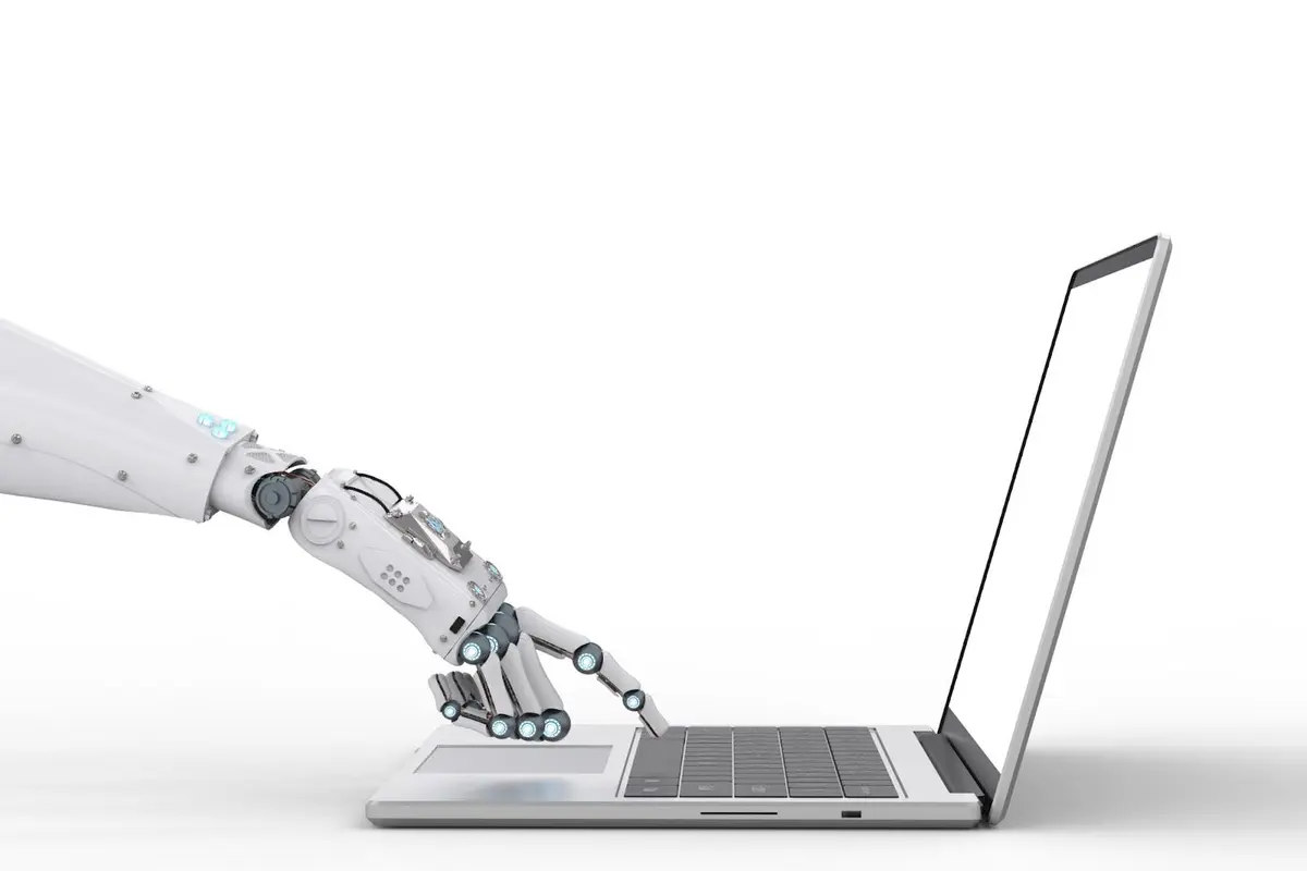 Robot hand pressing a laptop key representing artificial intelligence development and policy under Trump 2.0