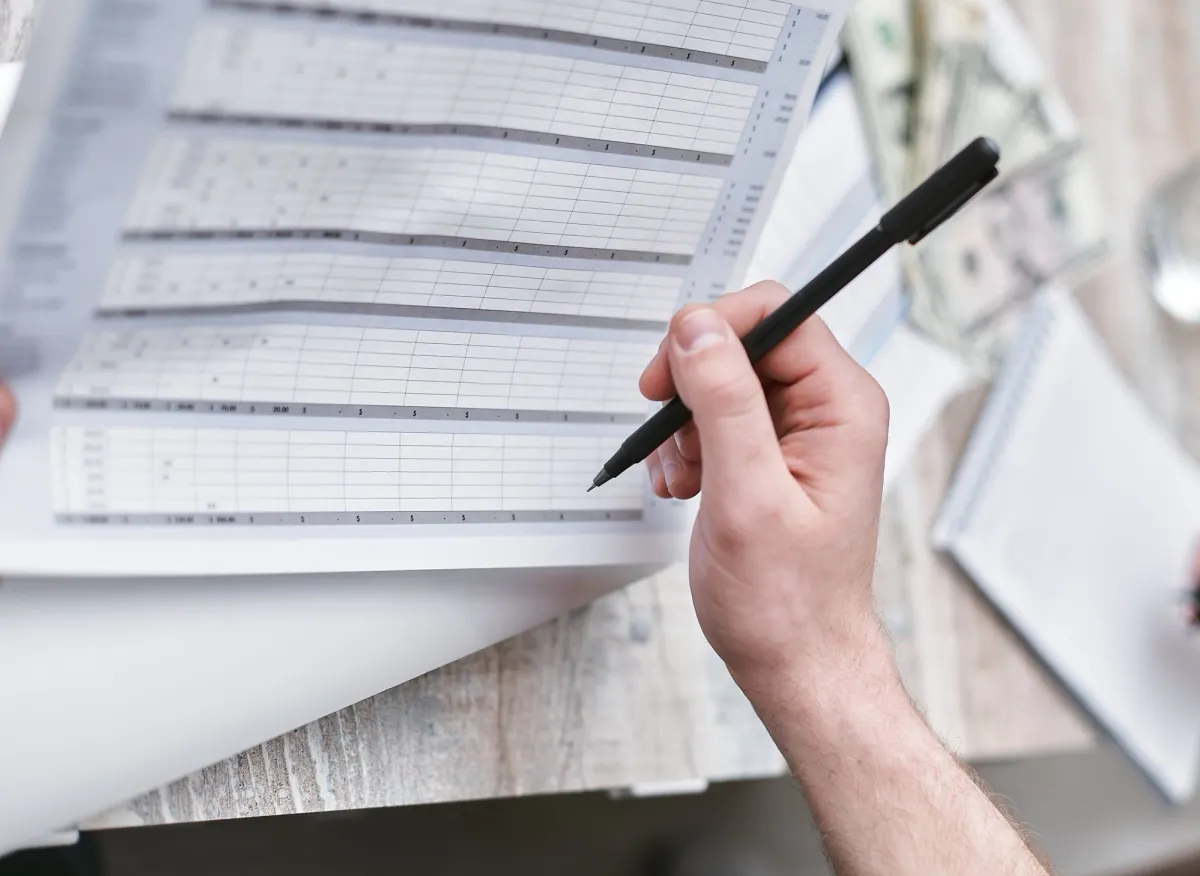 Person holding a financial spreadsheet and pen representing the process of building and maintaining a data map for business privacy compliance
