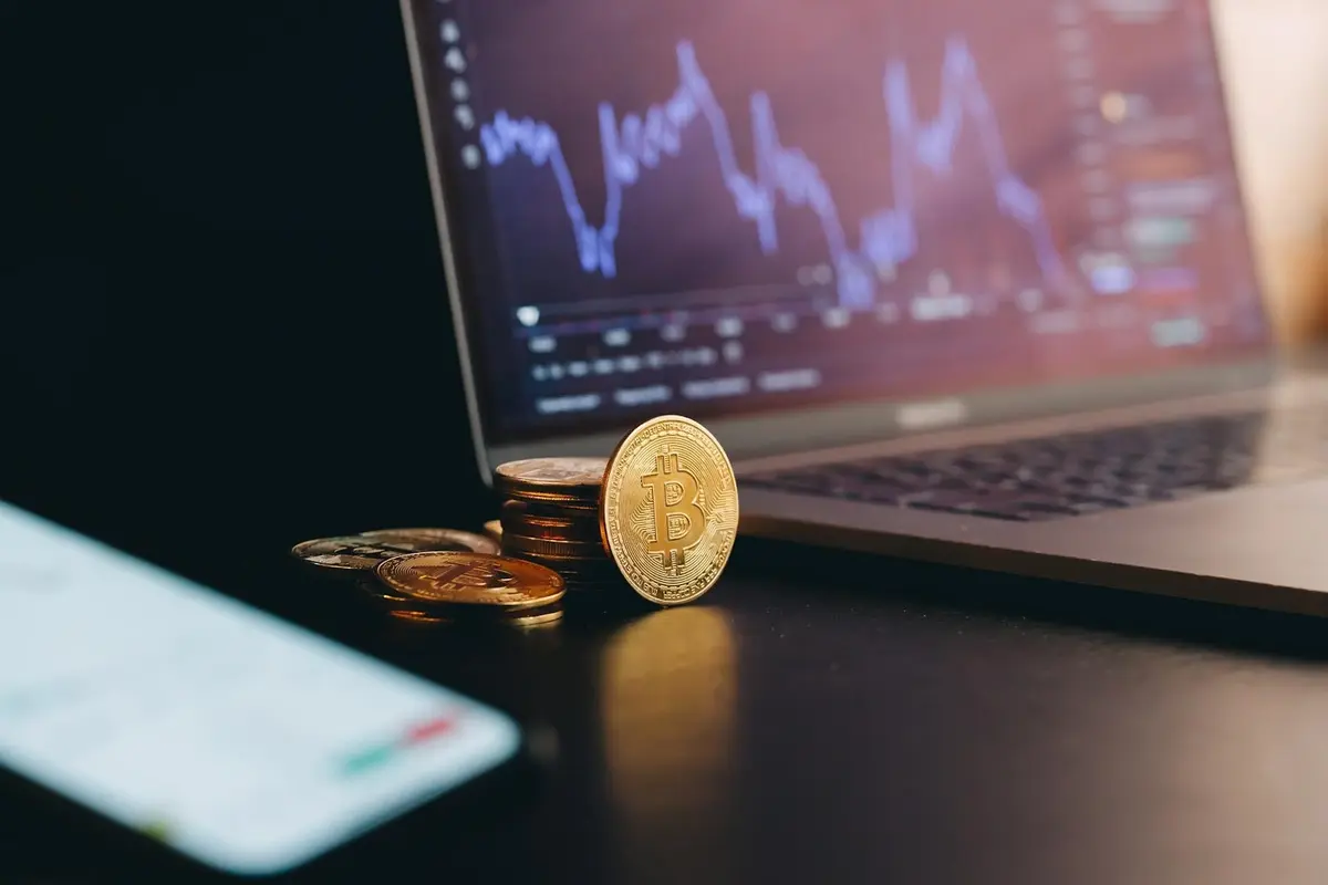 Bitcoin coin leaning against a laptop representing cryptocurrency market growth and regulatory outlook under the Trump administration